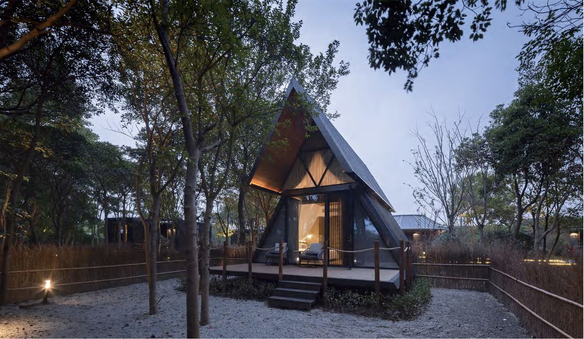 A-frame triangular cabin with glass front at dusk