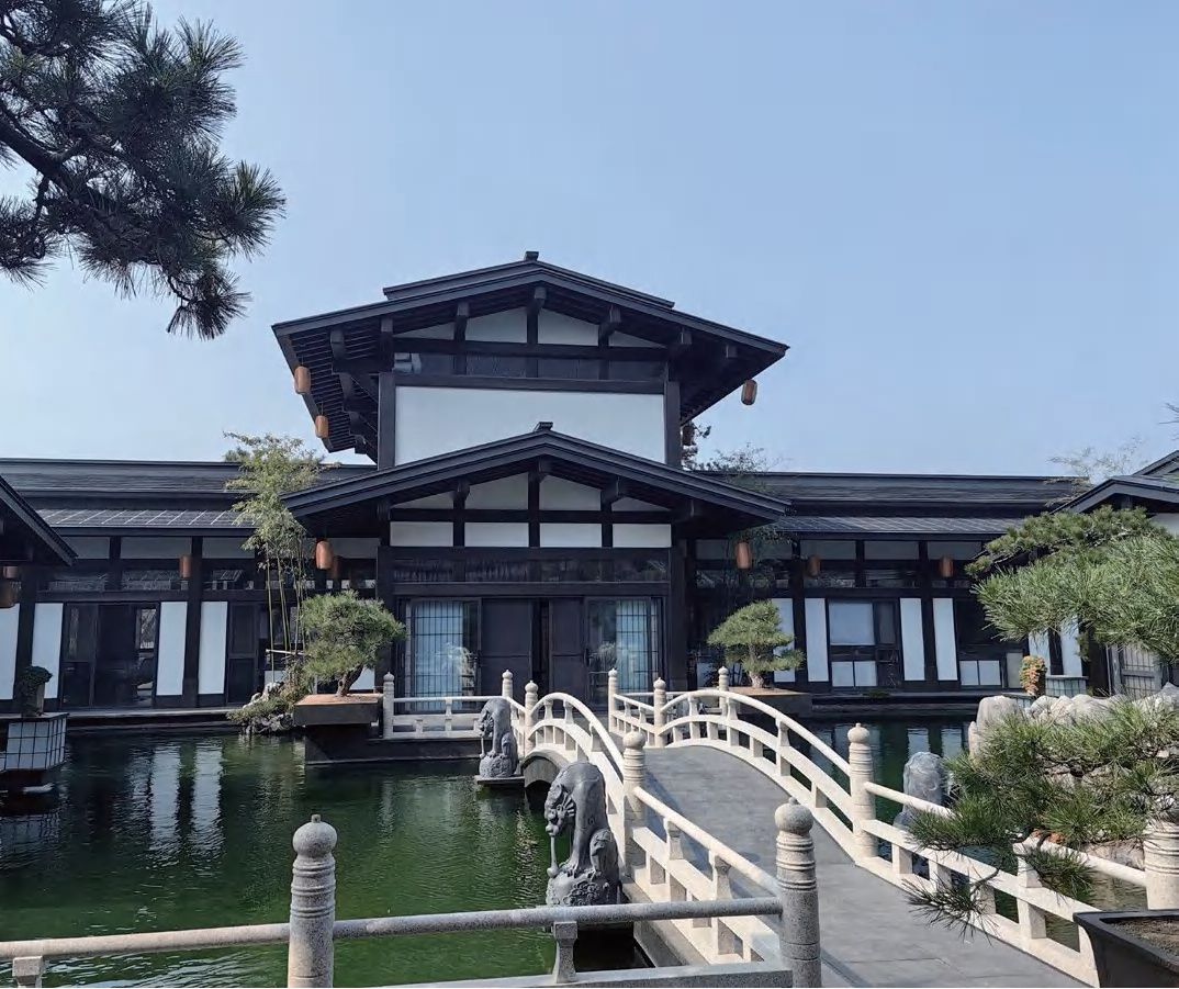 Courtyard villa with BIPV solar roof beside pond and arched bridge